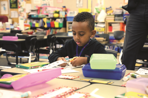 Preschool student cutting a piece of paper with scissors